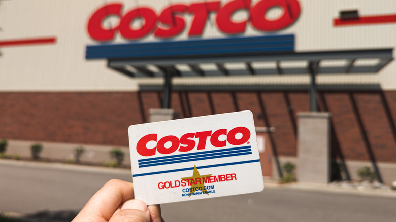 Person holding a Costco membership card outside of a warehouse location