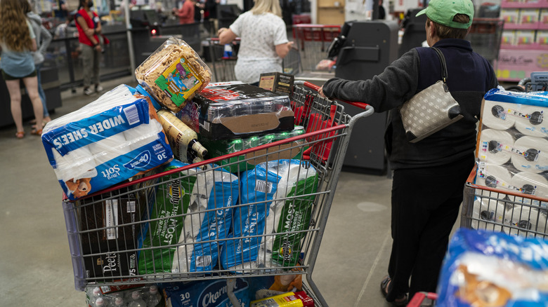 a Costco shopper holding onto an overfull cart inside the store