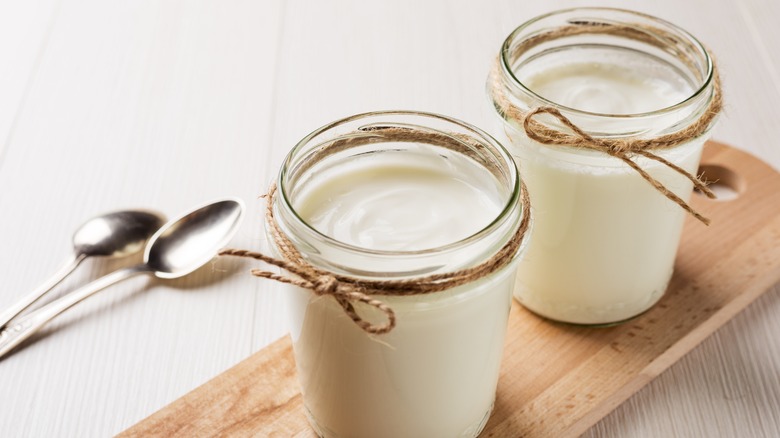 Two jars of homemade yogurt in a jar on a wood board