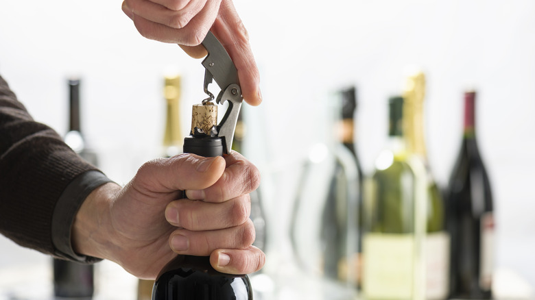 Opening bottle of wine with corkscrew