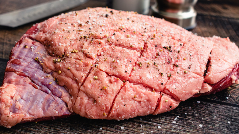 Scored and spiced steak on wooden surface