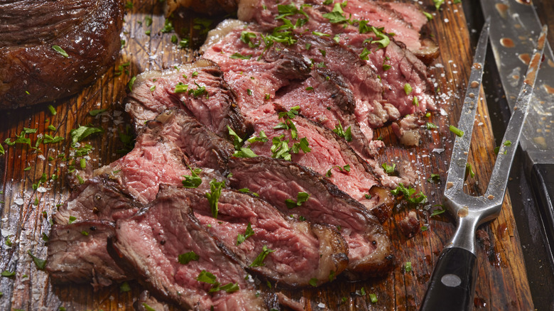 Ribbons of rare sliced skirt steak on a wood cutting board