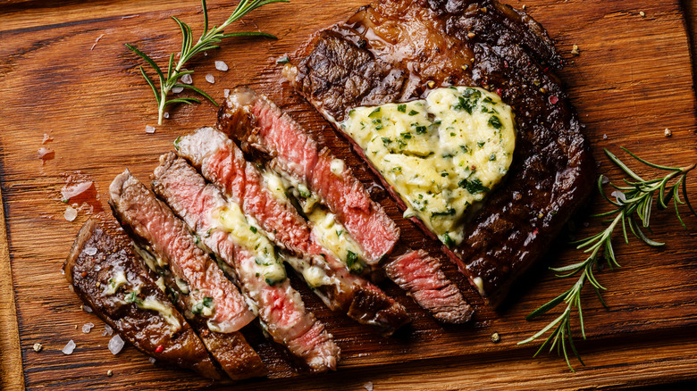 Steak with various seasonings on a wooden board