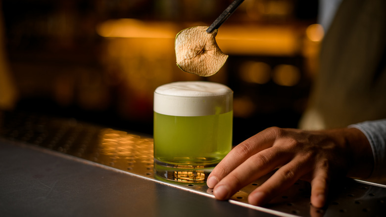 bartender garnishing foamy cocktail