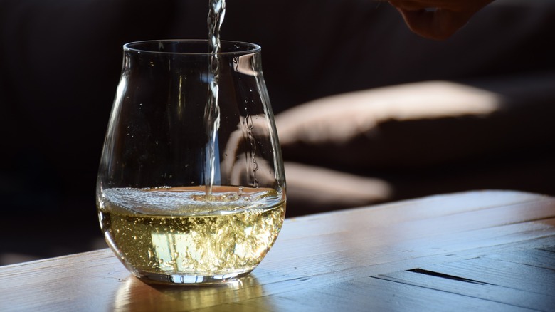 White wine being poured into a stemless wine glass