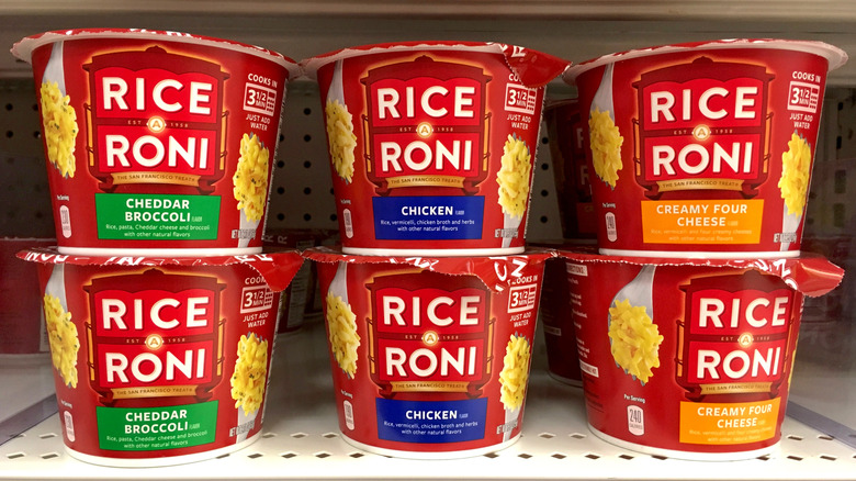 Rice A Roni cups in three flavors stacked on a store shelf.