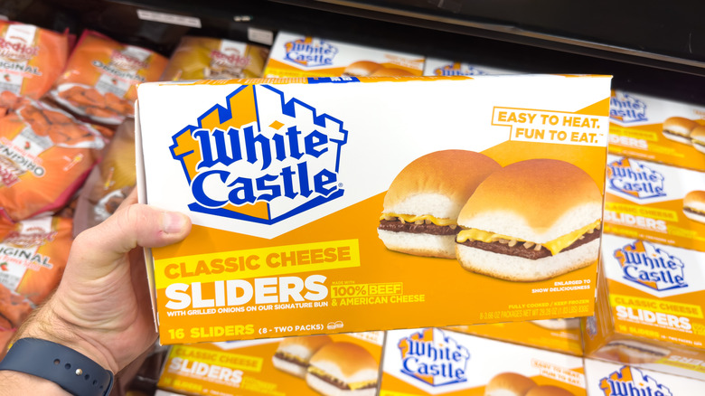 A male hand holding up a large box of White Castle Cheese Sliders.