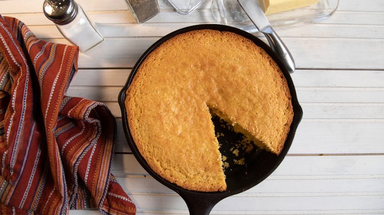 A skillet of cornbread with a slice taken out