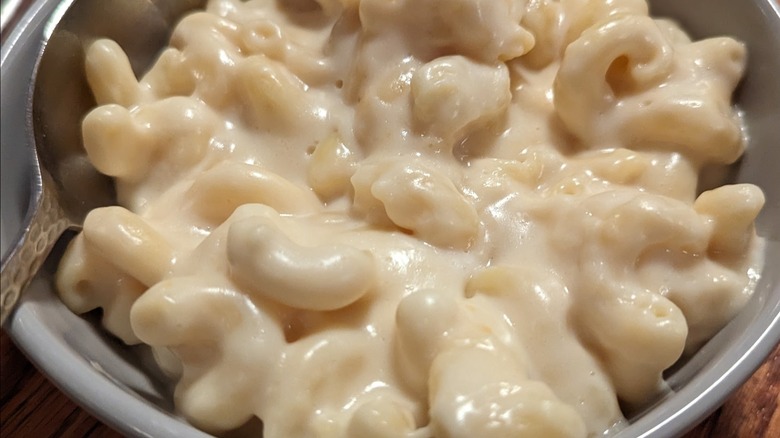 A bowl of creamy macaroni and cheese with a spoon.