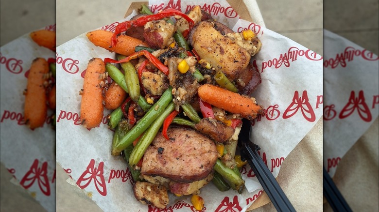 A pile of sausage, green beans, carrots, corn, potatoes, and other ingredients on a piece of white wax paper with the Dollywood logo on it.