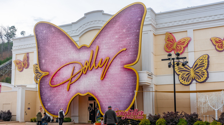 A pink, butterfly-shaped sign hangs over the entrance to a building. The butterfly bears the word "Dolly" written in gold cursive.