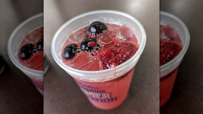 Berries floating in a glass of pink-colored lemonade.