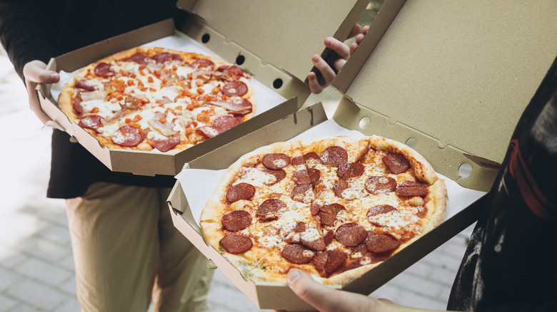 people holding pizzas in to go boxes