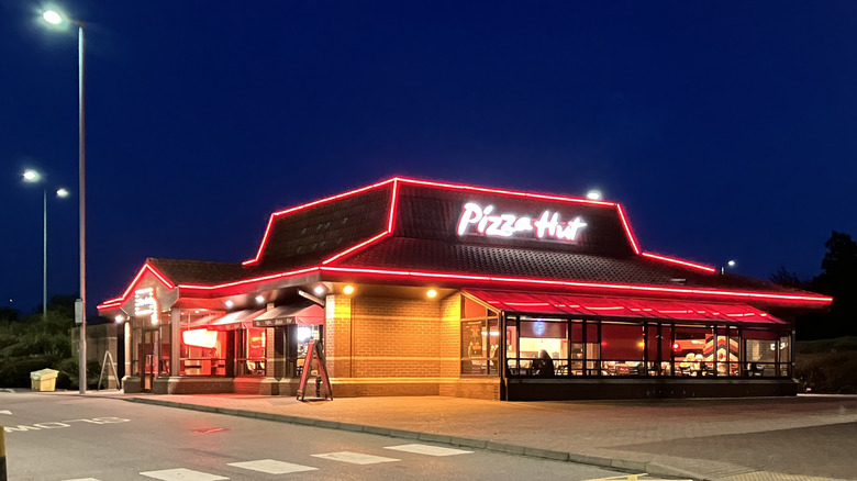 a pizza hut restaurant at night with lights outlining its roof