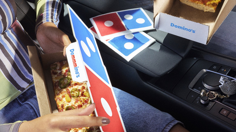 People eating Domino's personal pan pizza in the car
