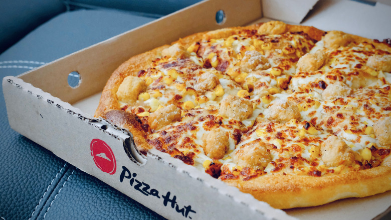 An open box of cheesy Pizza Hut pizza on a car seat