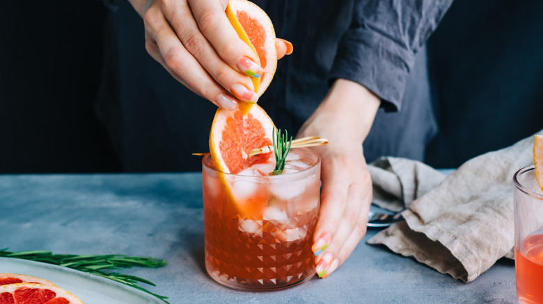 A bartender squeezes a grapefruit into a cocktail