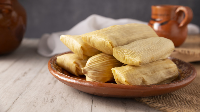 a stack of wrapped tamales on a clay plate