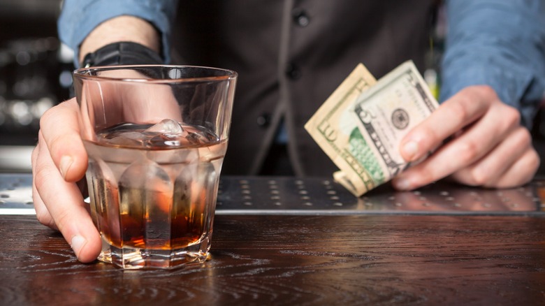 A bartender's hands accepting a tip and serving a drink