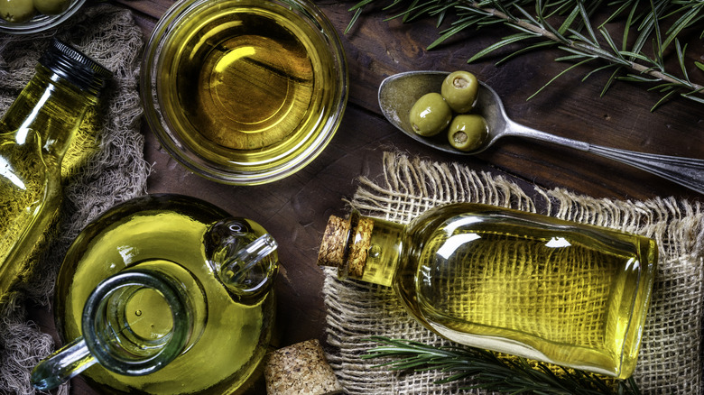 bottles of olive oil and olives on a wood table