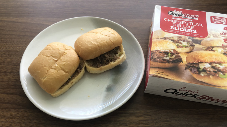 A pair of Gary's quick steak Cheesesteak Deluxe sliders on a plate next to the Box they came from