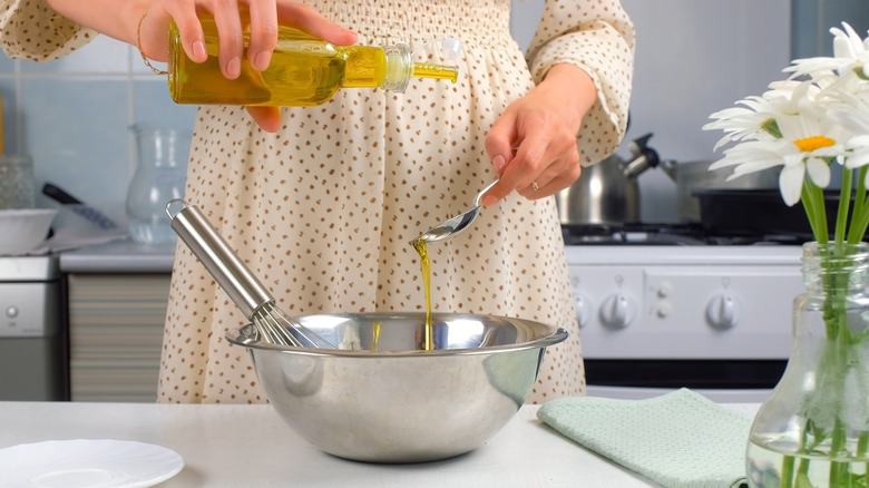 Person pouring oil metal bowl