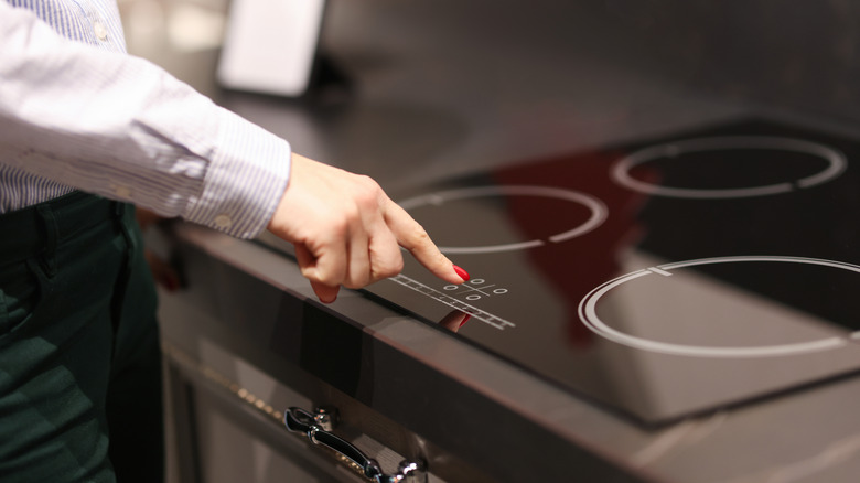 Person touching button induction stove