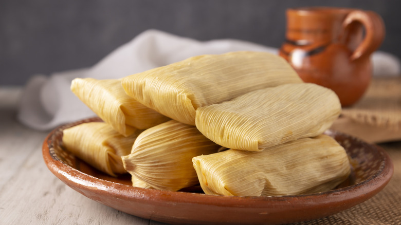corn husk tamales on a clay plate