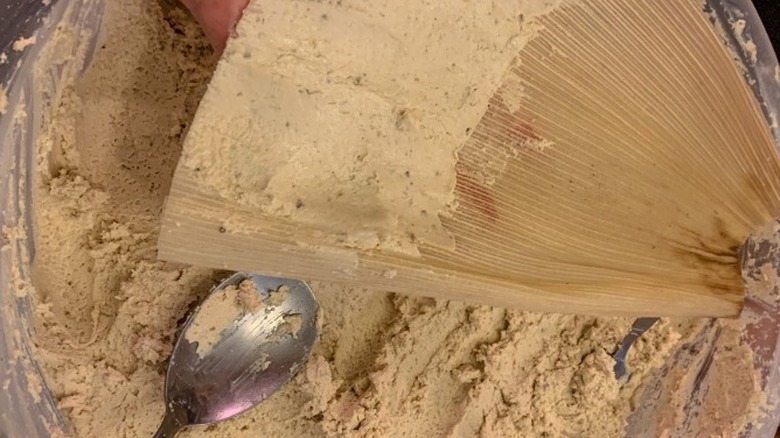 spreading masa onto corn husks to make tamales