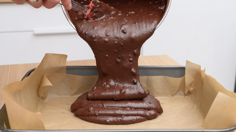 Decadent brownie mix being slowly poured into a pan