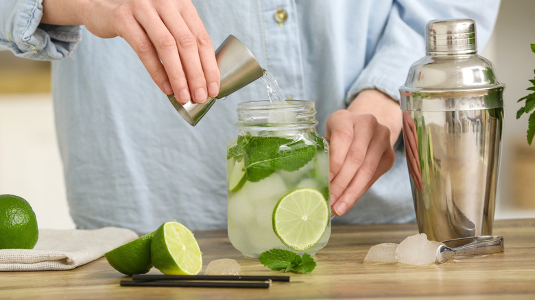 Hands mixing cocktail in glass jar