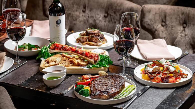 meals on table at steakhouse with glasses of wine