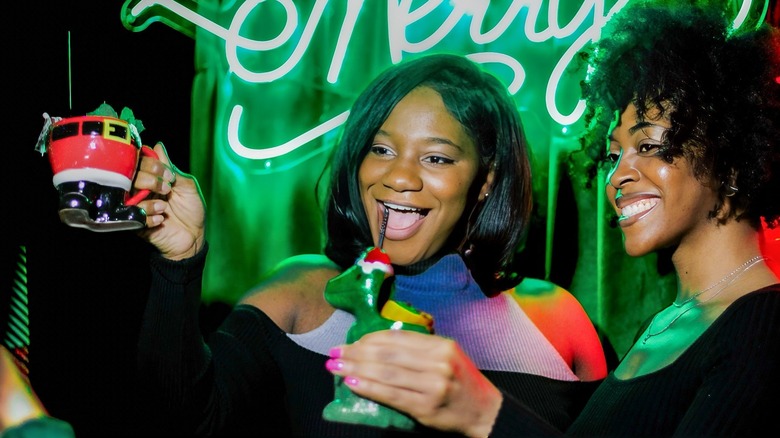 Two women toasting with Christmas drinks at the Miracle pop-up bar.