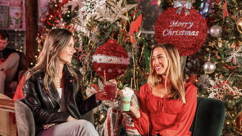 Two women toasting the holidays in a decorated bar.
