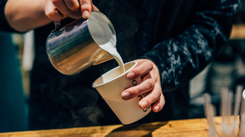 Barista pouring milk into a cup