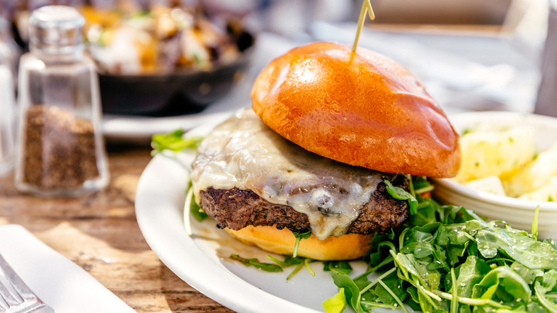 A beef hamburger and arugula on a plate