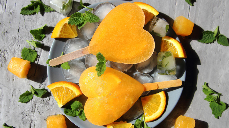 Heart-shaped orange juice popsicles on plate