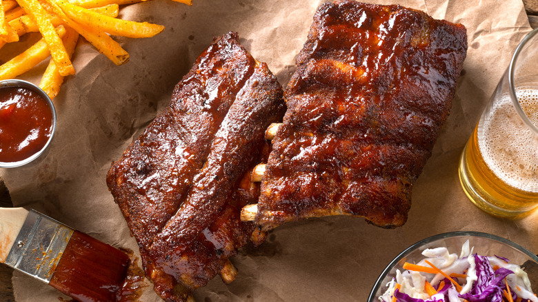 racks of baby back ribs on a paper with sides