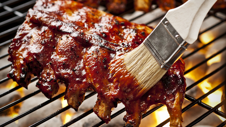 a rack of ribs on a grill being painted with sauce
