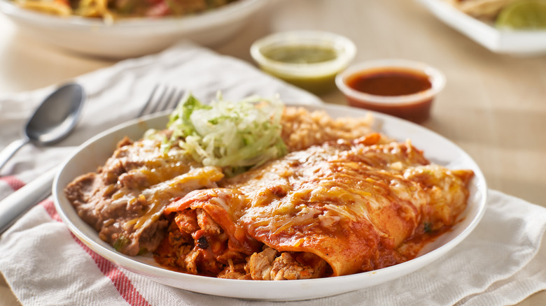 a plate of enchiladas with red and green sauces and beans