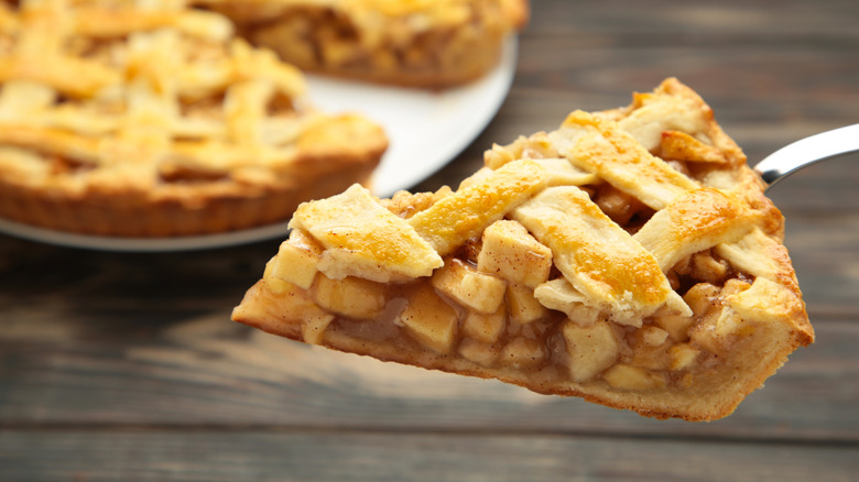 Slice of apple pie in front of the rest of the pie