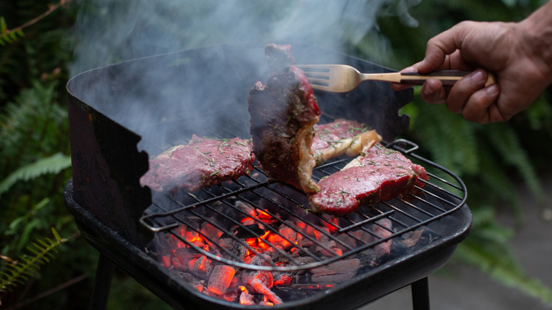 steaks grilling on small charcoal grill