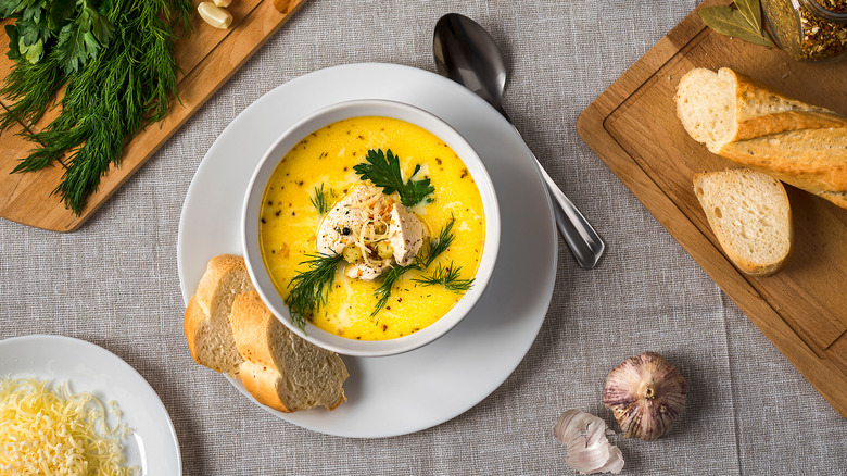 A serving of chicken cordon bleu soup in a white bowl, garnished with cheese and parsley