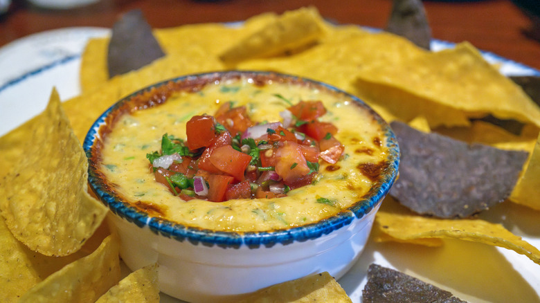 Chips next to bowl of queso topped with pico de gallo