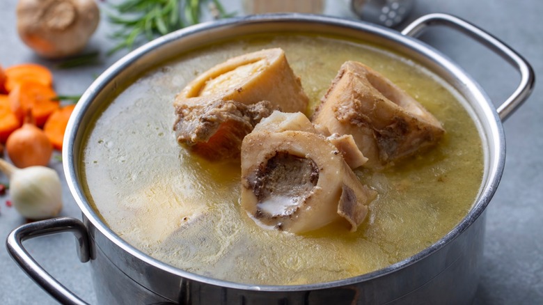 A stock pot full of broth with beef bone sticking out