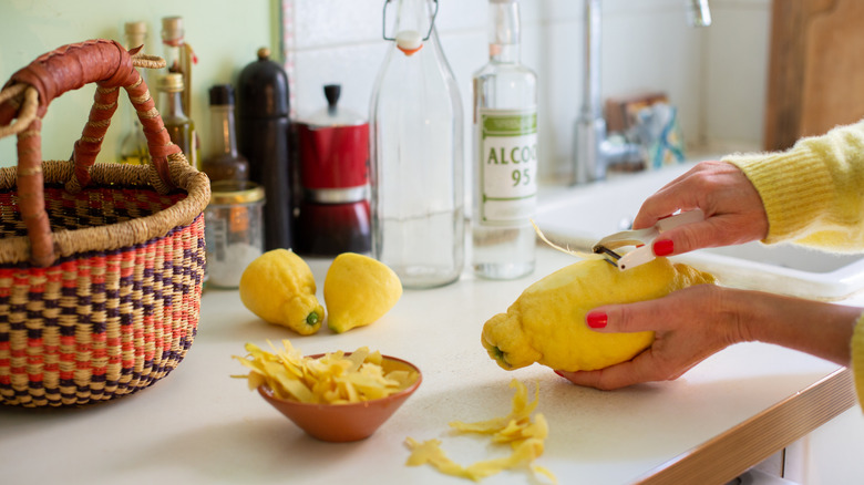 Hands peeling lemon near kitchen sink