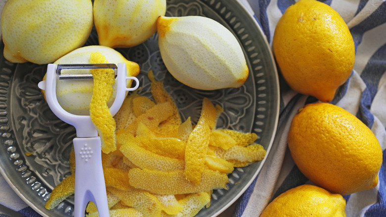 Bowl of peeled lemons, peeler, and peels