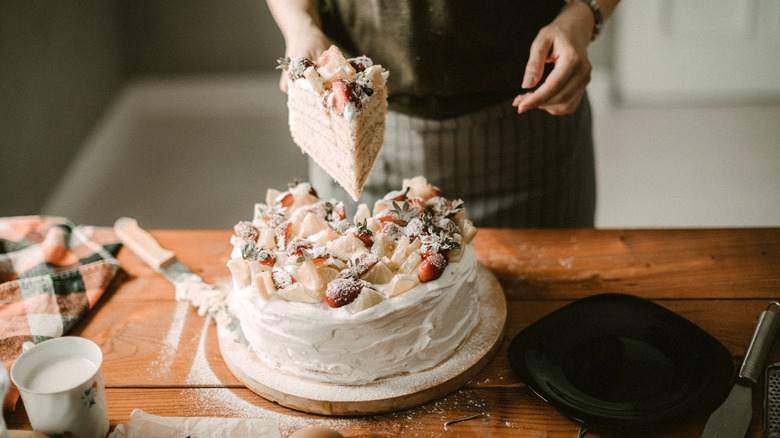 Woman's hands cutting decorated cake