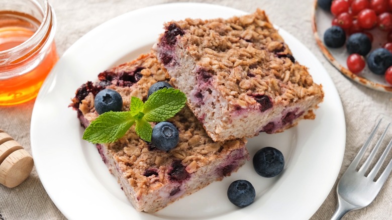 Two baked oatmeal bars with blueberries on white plate