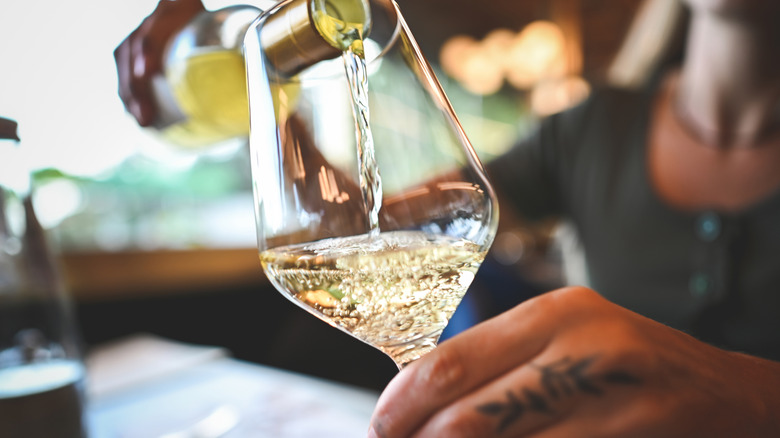 Person pouring a glass of white wine